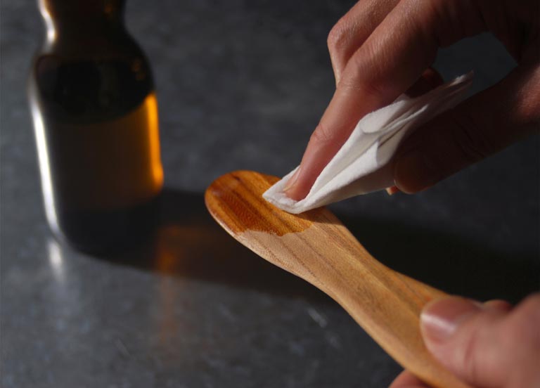オイルを塗っている木製のバターナイフ