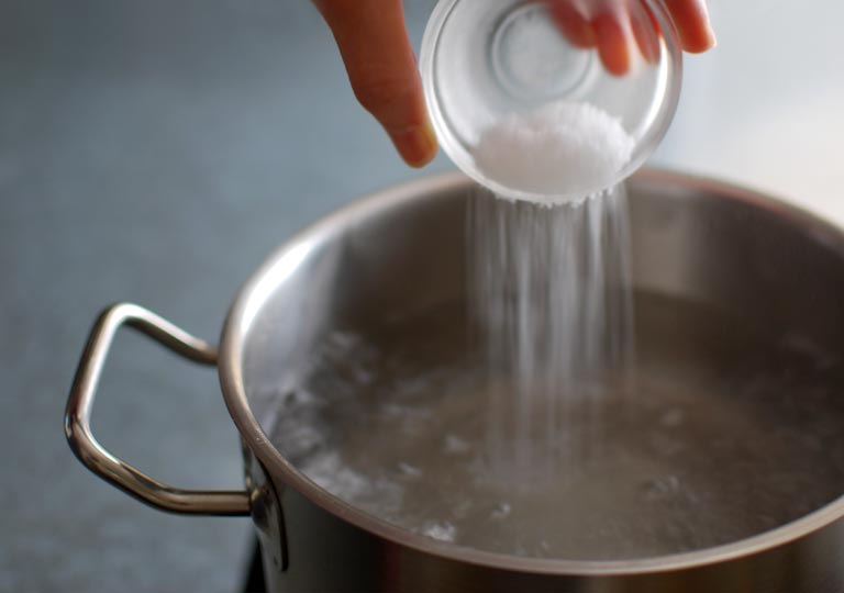 鍋の中の沸騰したお湯に塩を入れる様子